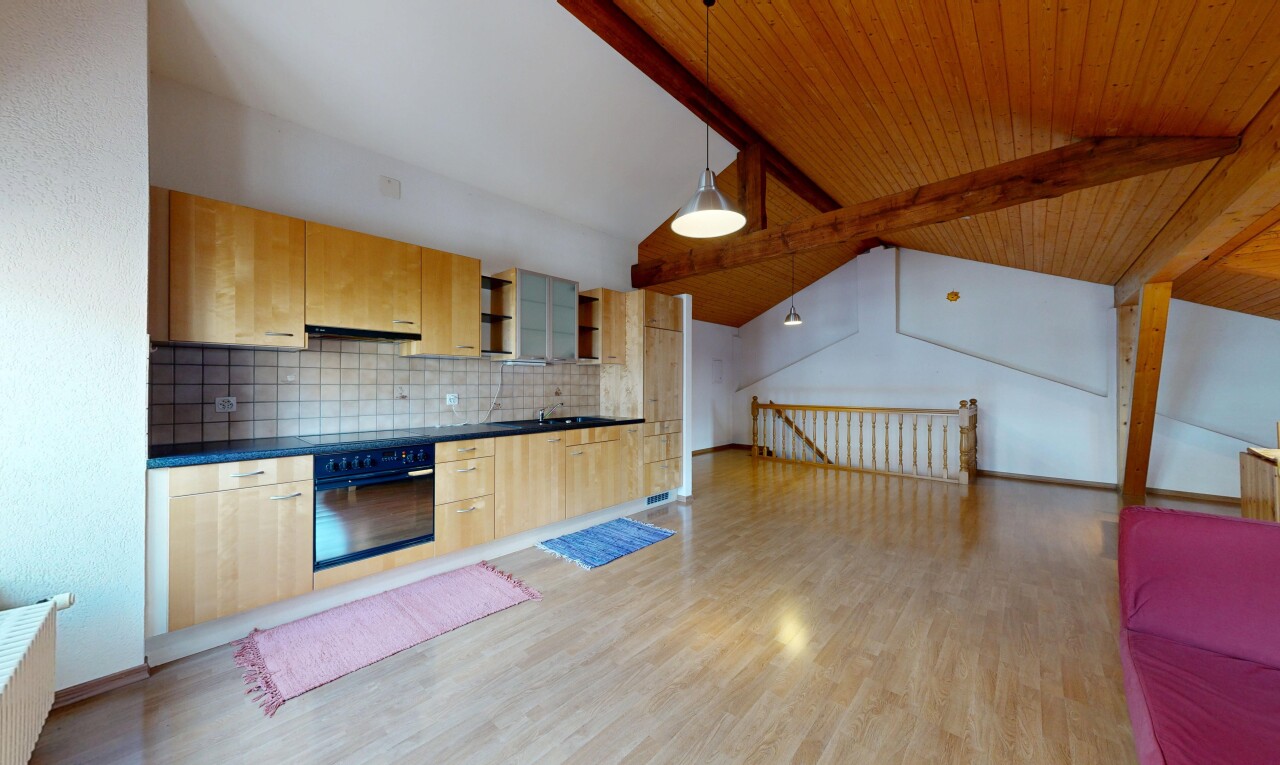 cuisine avec plafond à poutres, beamed ceiling, plans de travail, dark countertops, et armoires marron clair