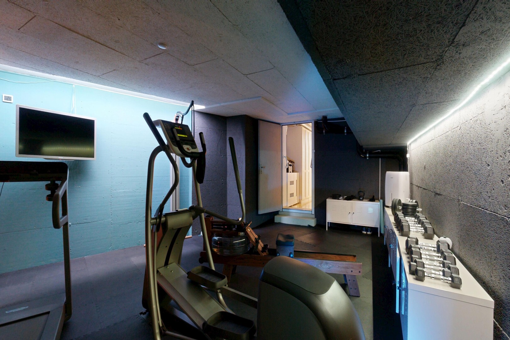fitnessstudio mit fernseher, keller, inside property, dark floor, und concrete floor