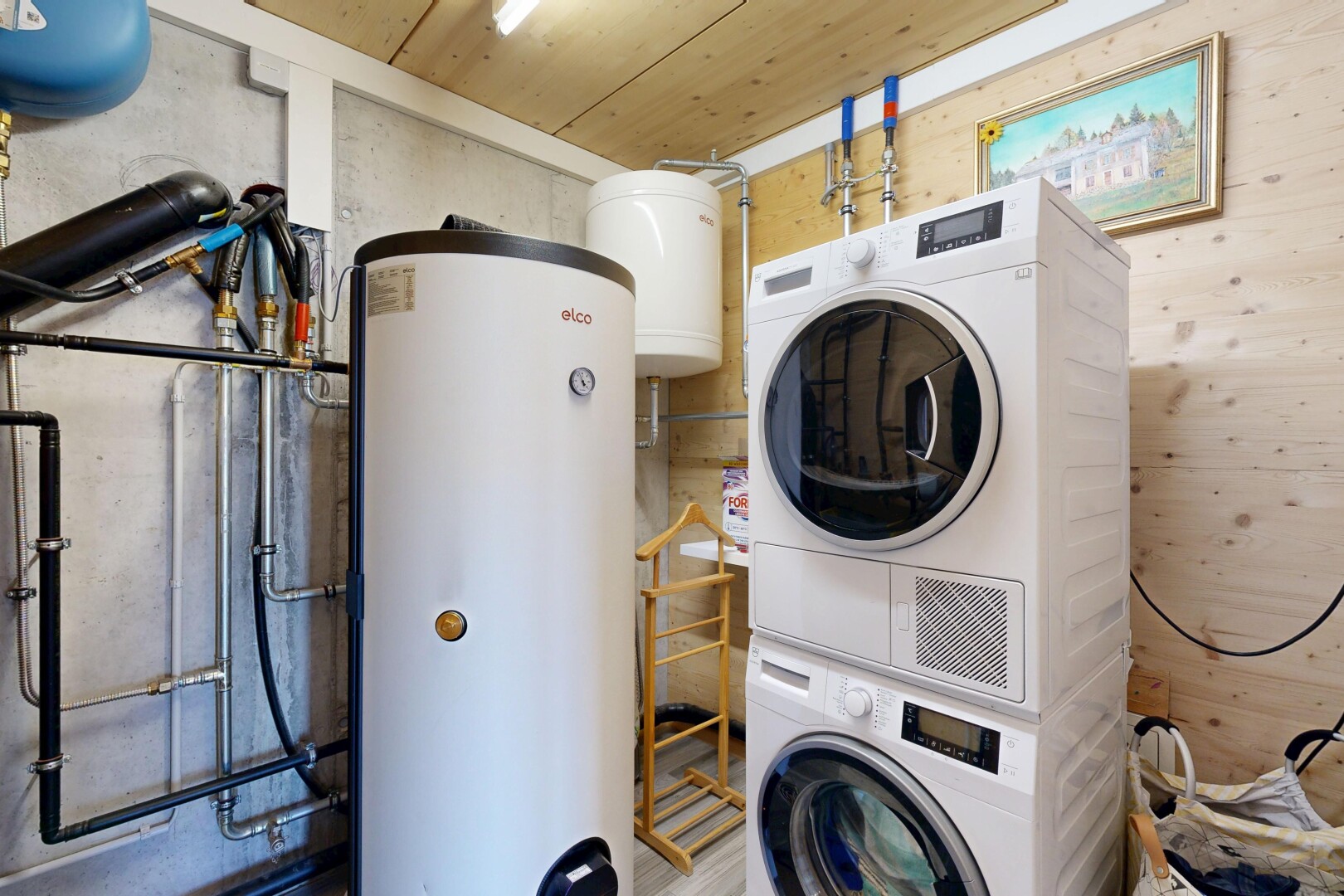 laundry area featuring gas water heater, stacked washer / drying machine, and wooden ceiling