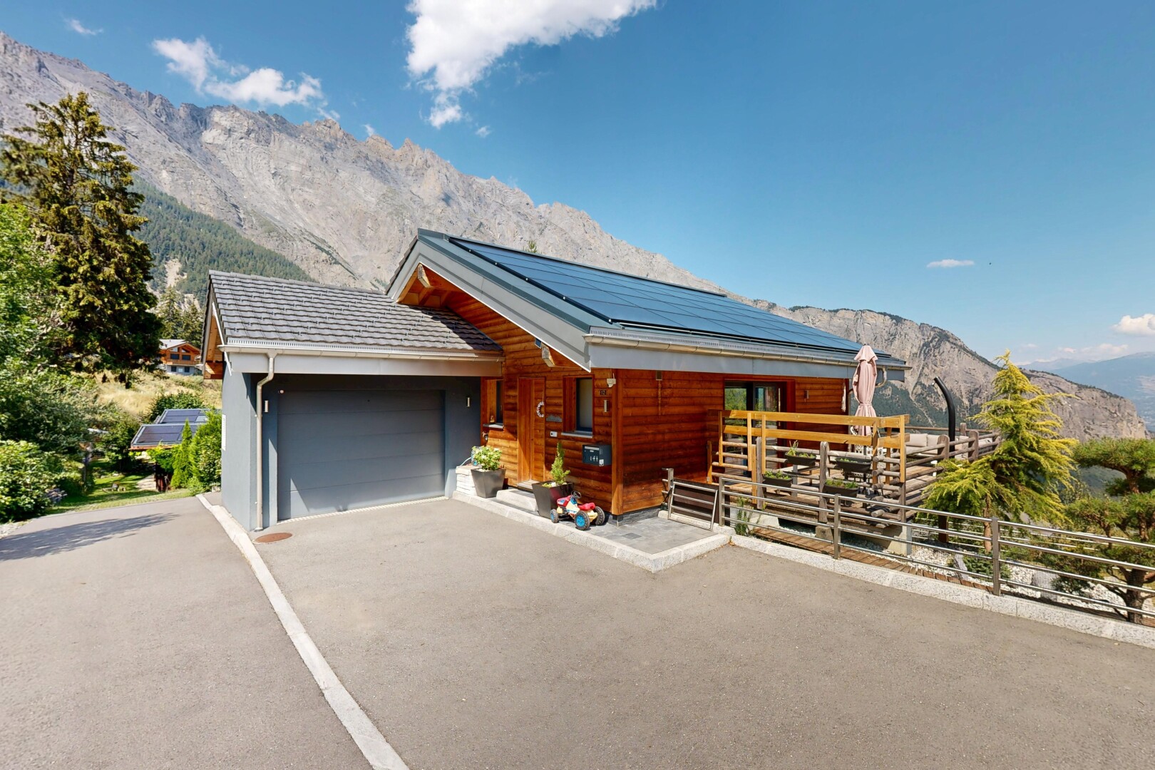 view of property with a mountain view, solar panels, a garage, covered porch, and asphalt driveway