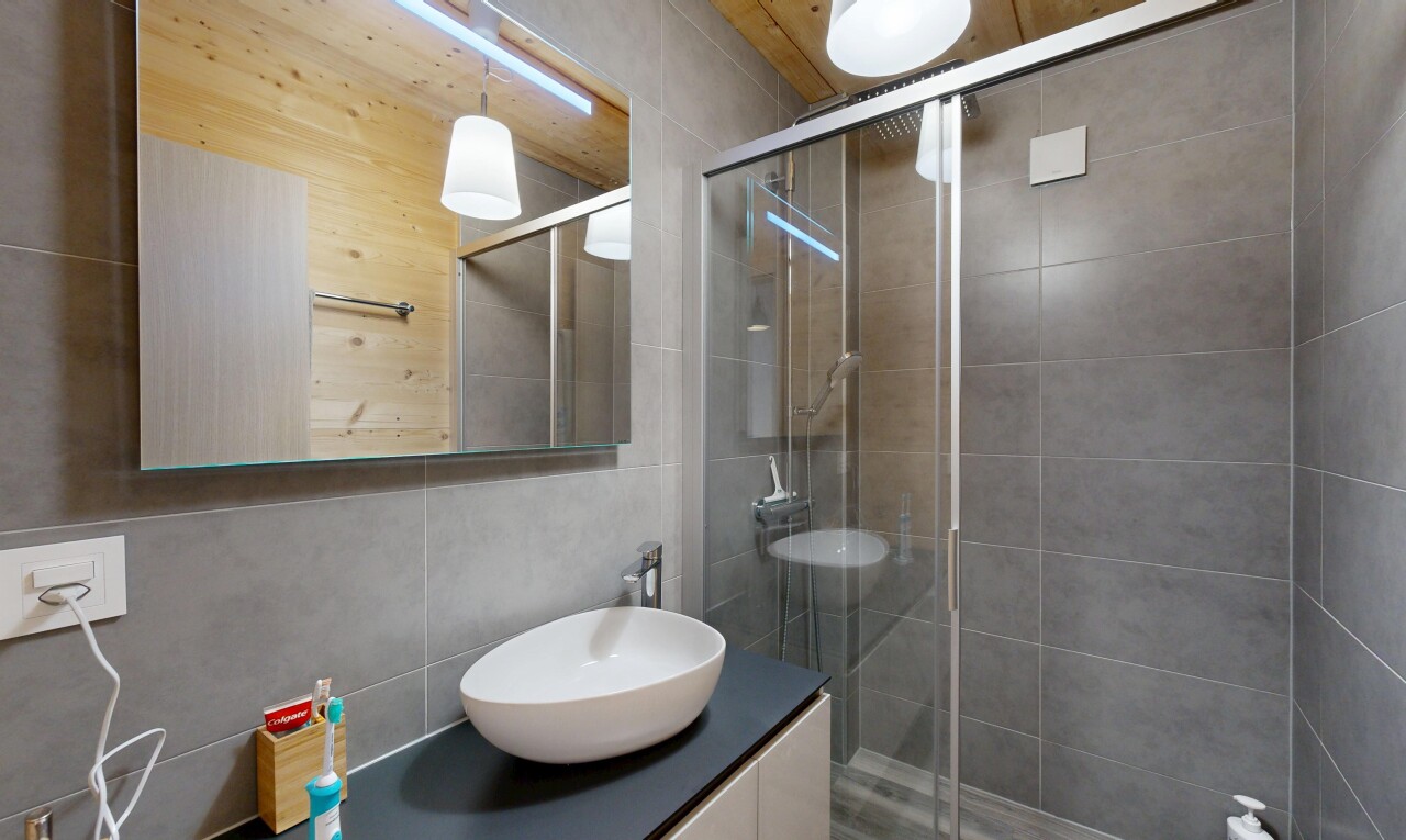 full bath with a shower stall, vanity, and tile walls