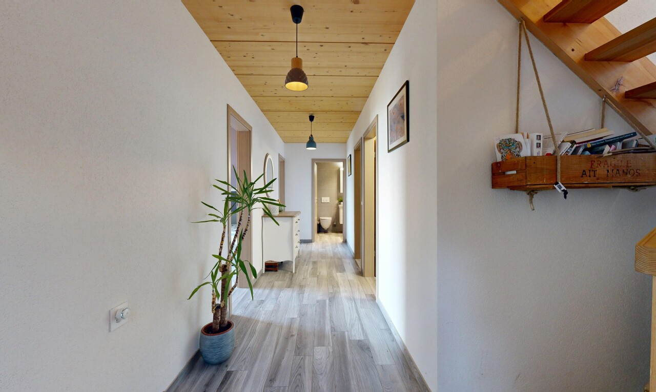 hallway with hanging light fixtures, wood ceiling, and light wood-style floors