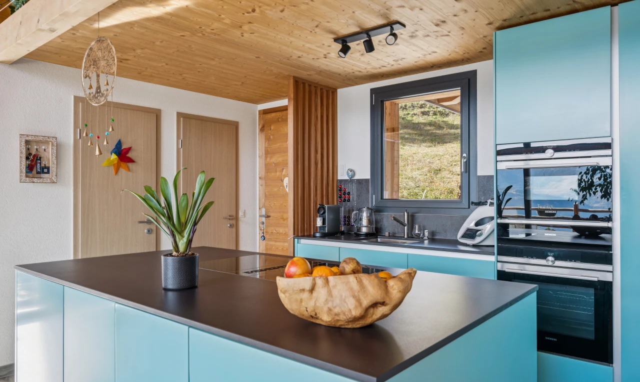 cuisine avec armoires bleues, blue cabinets, plans de travail, dark countertops, et plafond en bois