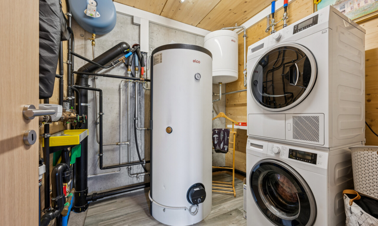 buanderie avec chauffe-eau, lave-linge et sèche-linge superposés, réservoir d'expansion d'eau, buanderie, et wood finish floor