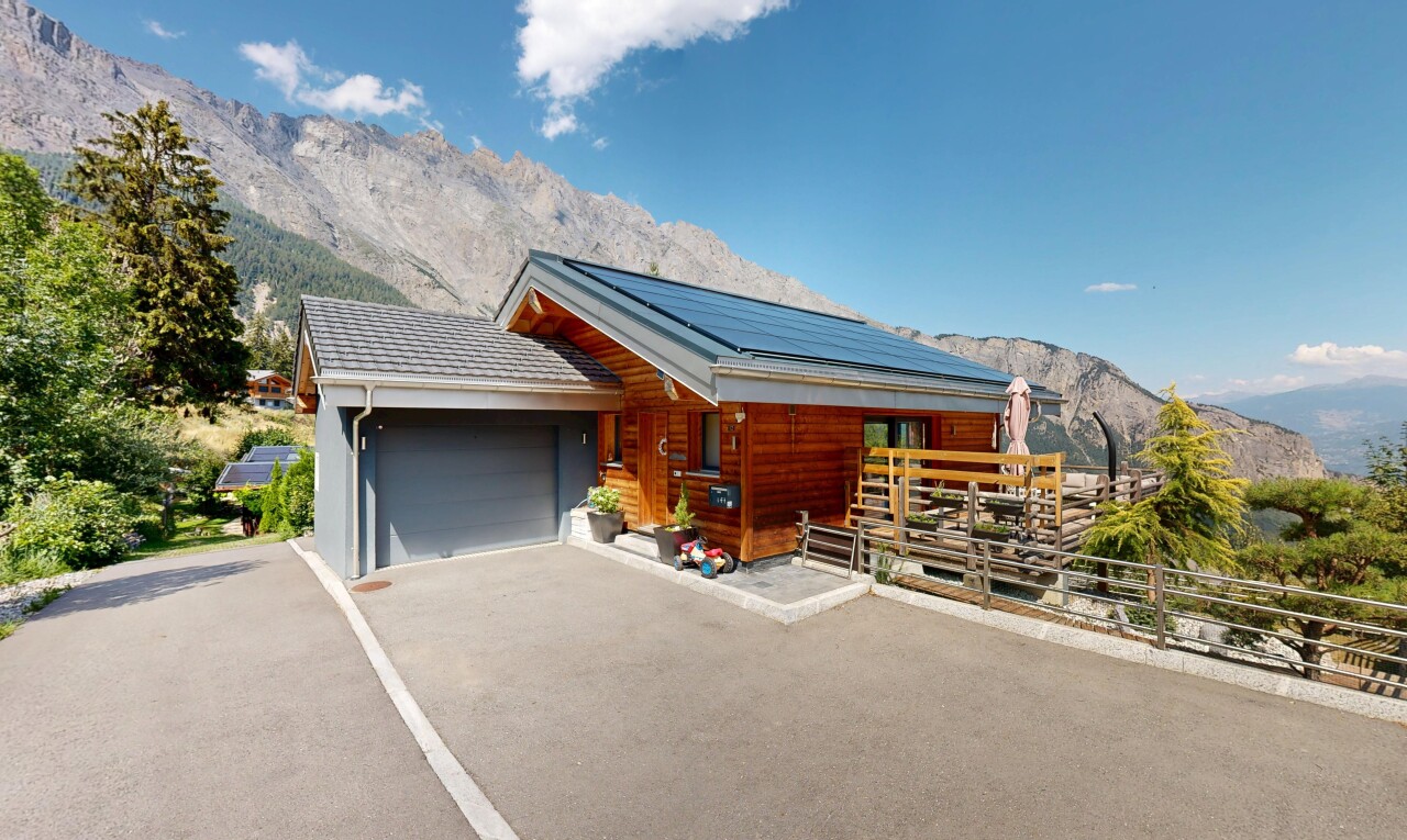 view of property with a mountain view, solar panels, a garage, covered porch, and asphalt driveway