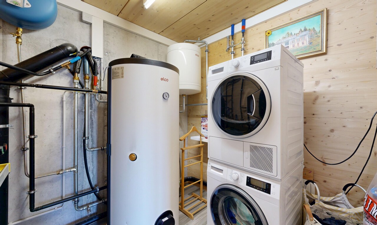 laundry area featuring gas water heater, stacked washer / drying machine, and wooden ceiling