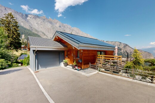 view of property with a mountain view, solar panels, a garage, covered porch, and asphalt driveway