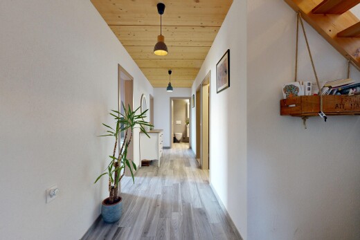 hallway with hanging light fixtures, wood ceiling, and light wood-style floors