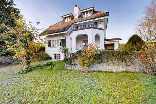 outdoor house featuring a balcony, a yard, a chimney, and stucco siding