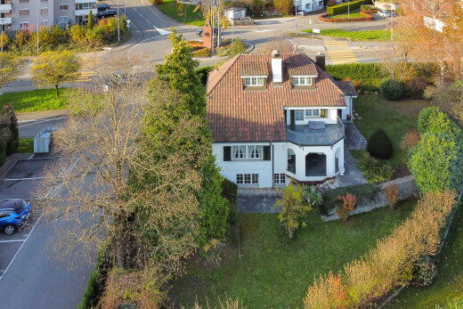 view of property with a patio, a yard, a tile roof, and uncovered parking