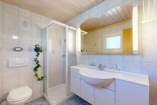 bathroom featuring tile walls, a shower stall, toilet, vanity, and wood ceiling