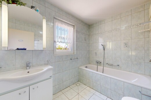 bathroom with tile walls, tiled bath, tile patterned flooring, and vanity