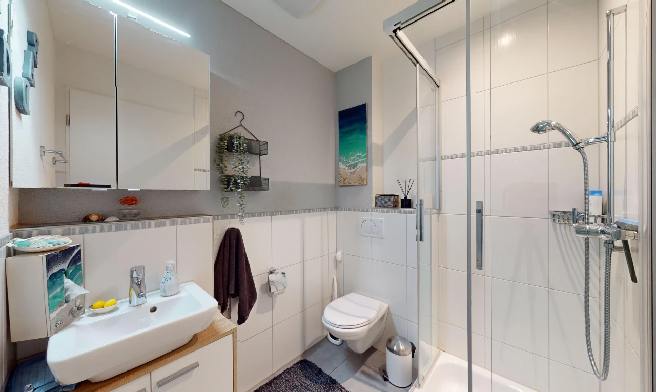 salle de bains avec mur carrelé, vasque, meuble-lavabo, miroir, et douche