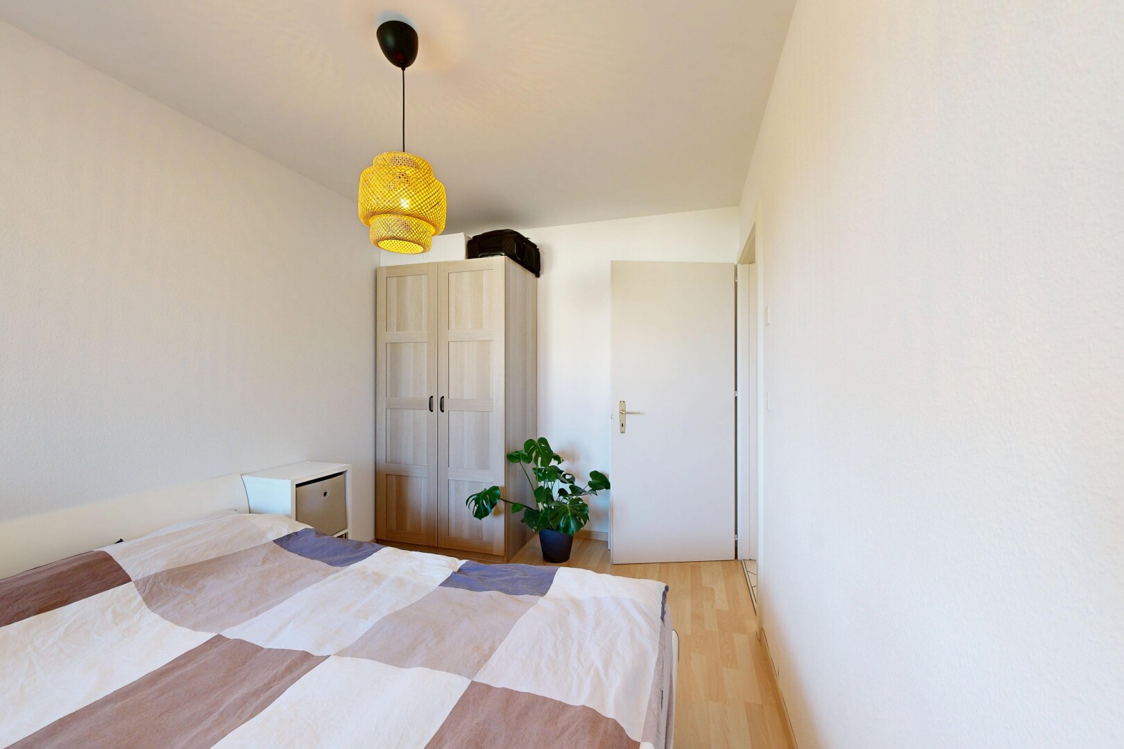 chambre avec éclairage suspendu, wood finish floor, sol en finition bois, drywall, et cloison sèche