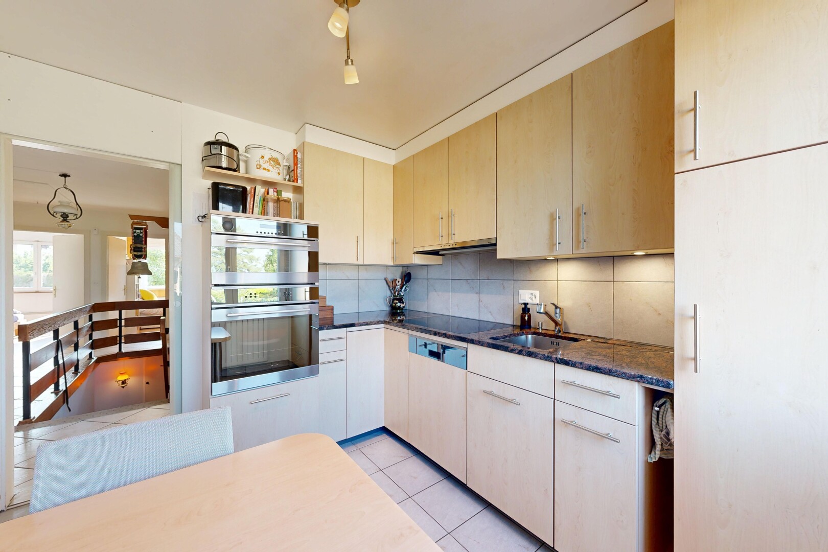 cuisine avec light floor, dark countertops, armoires marron clair, light brown cabinets, et dosseret
