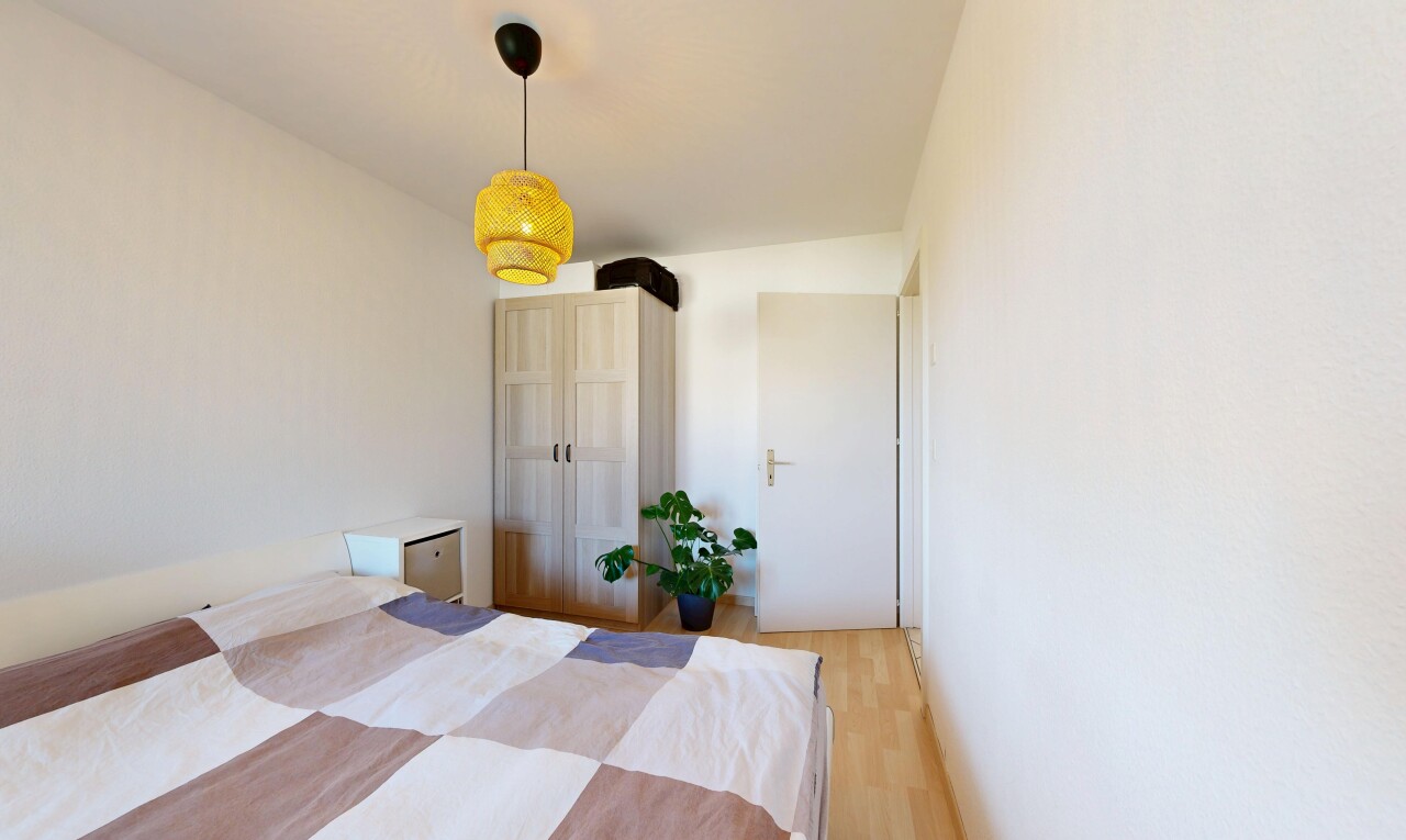 chambre avec éclairage suspendu, wood finish floor, sol en finition bois, drywall, et cloison sèche