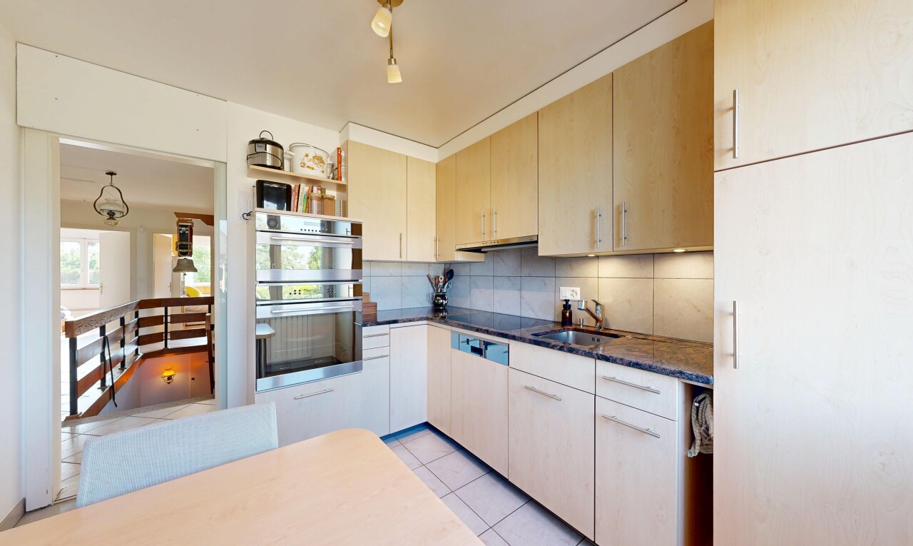 cuisine avec light floor, dark countertops, armoires marron clair, light brown cabinets, et dosseret