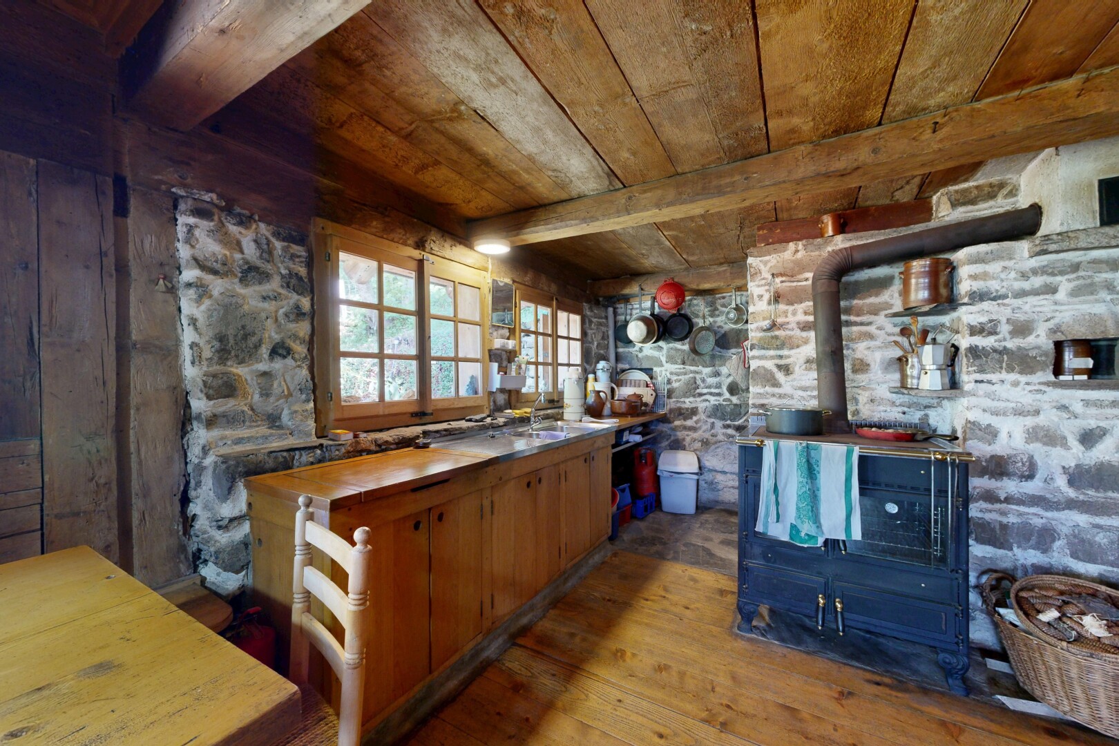 cuisine avec poêle à bois, sol en finition bois, wood finish floor, plafond en bois, et wood ceiling