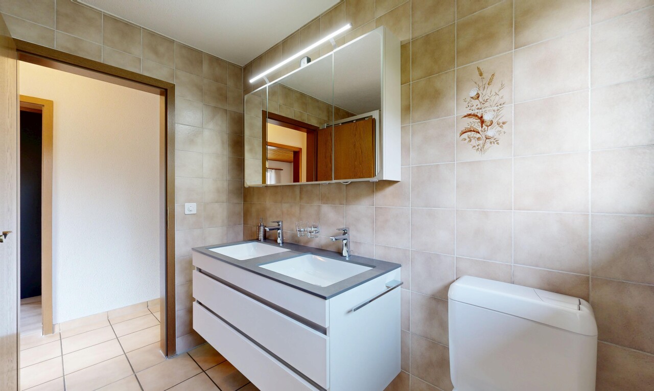 full bath featuring tile walls, double vanity, and light tile patterned flooring