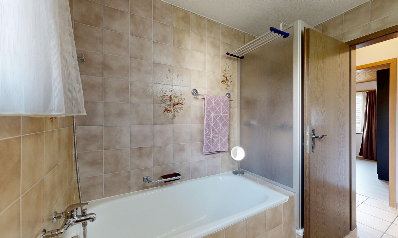 bathroom featuring a shower and tiled tub