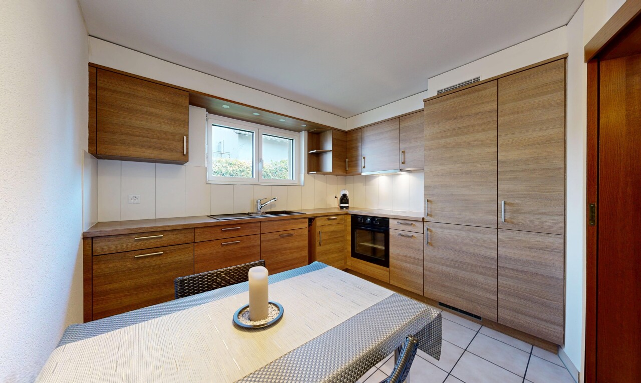kitchen with black oven, light tile patterned flooring, brown cabinets, and light countertops