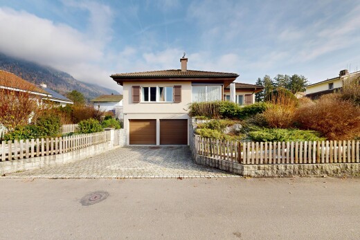 view of property with a fenced front yard, an attached garage, driveway, a chimney, and stucco siding