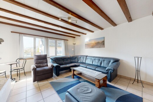 living room with light tile patterned floors and beam ceiling