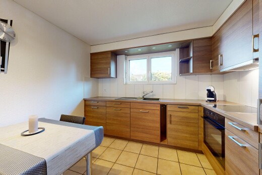 kitchen with black appliances, brown cabinetry, light countertops, light tile patterned flooring, and ventilation hood