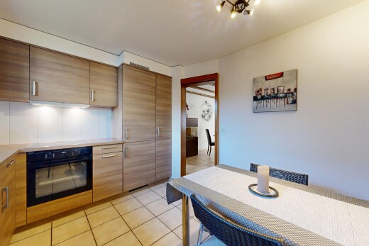 kitchen featuring black oven, light tile patterned flooring, light countertops, and modern cabinets