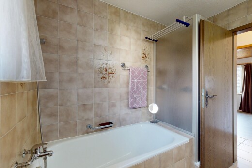 bathroom featuring a shower and tiled tub
