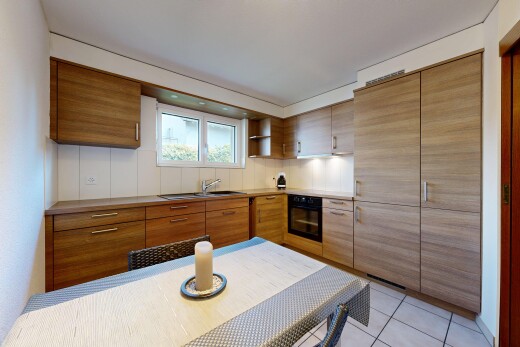 kitchen with black oven, light tile patterned flooring, brown cabinets, and light countertops