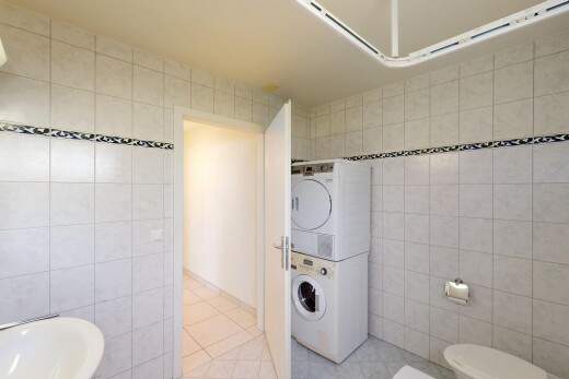 salle de bains avec lave-linge et sèche-linge superposés, tile wall, mur en carrelage, tile floor, et sol en carrelage