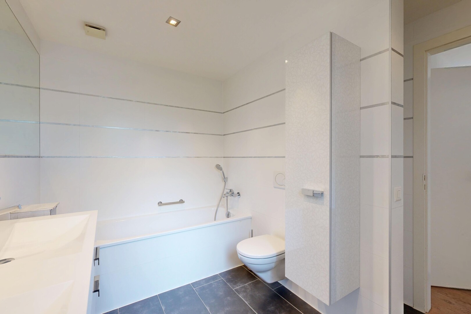 bathroom featuring vanity, dark tile patterned floors, and a bath