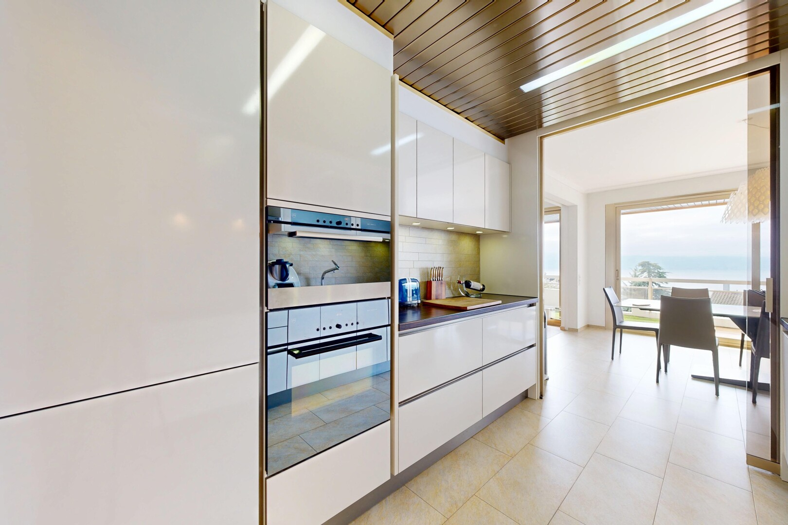 kitchen featuring white cabinets, dark countertops, stainless steel double oven, modern cabinets, and tasteful backsplash