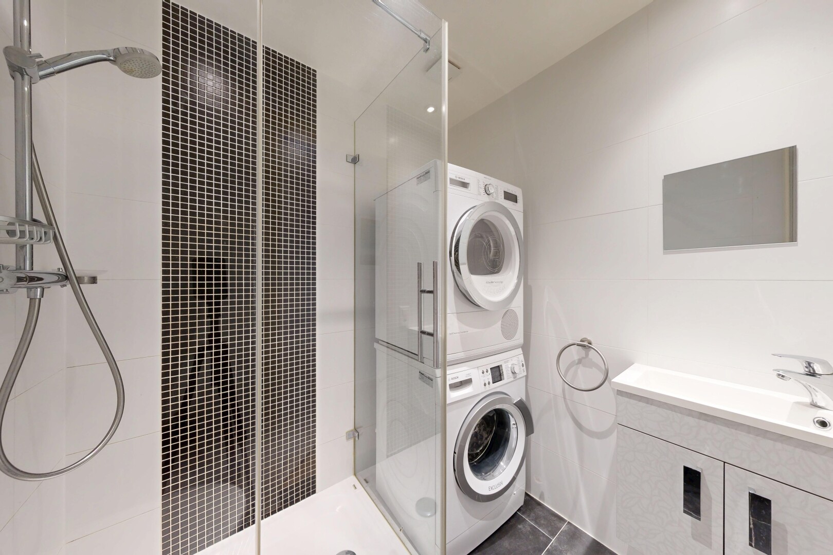 bathroom with a heating unit, vanity, a stall shower, stacked washer / drying machine, and dark tile patterned flooring