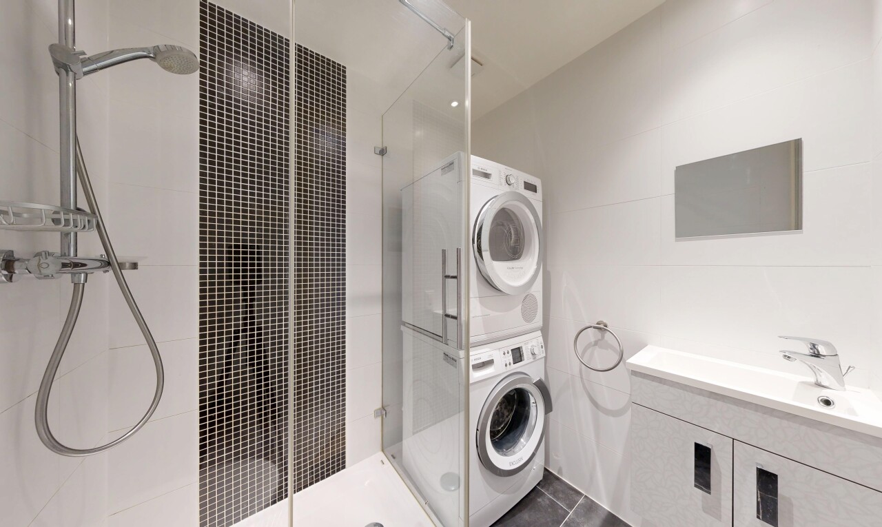 bathroom with a heating unit, vanity, a stall shower, stacked washer / drying machine, and dark tile patterned flooring