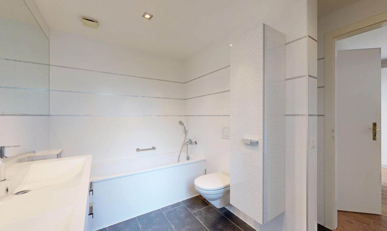 bathroom featuring vanity, dark tile patterned floors, and a bath