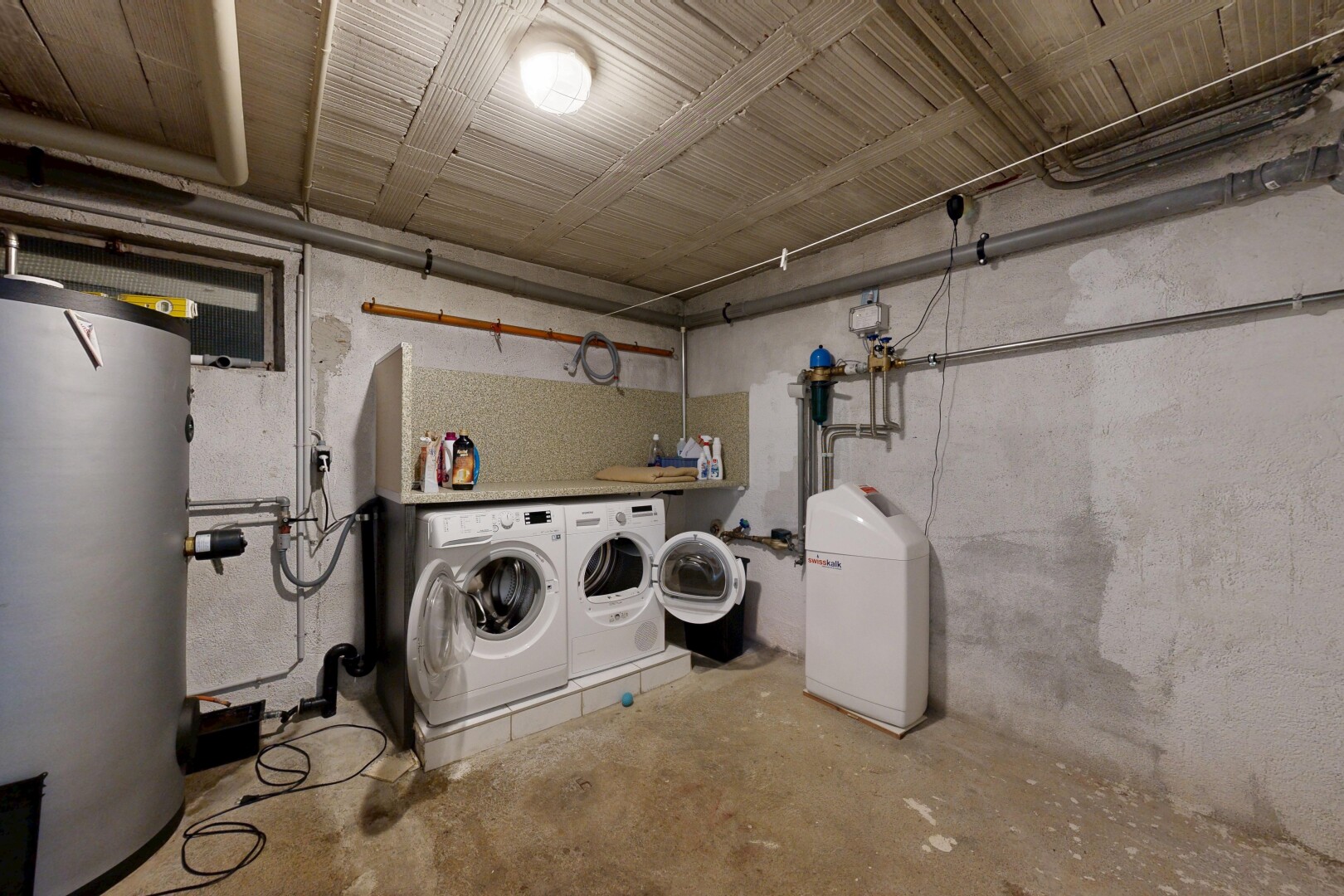 wäschekammer mit concrete wall, concrete floor, wasserkocher, unfinished concrete floor, und keller