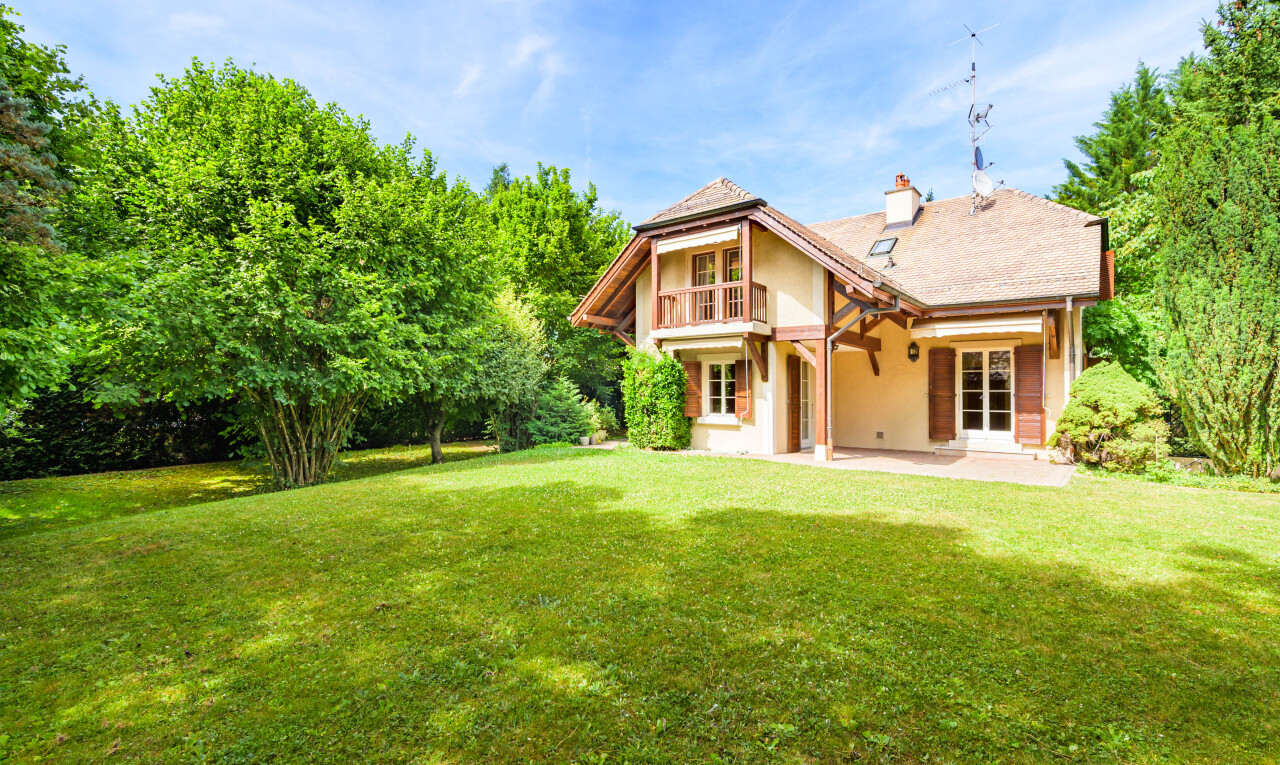 view of home featuring a patio, a lawn, and a chimney