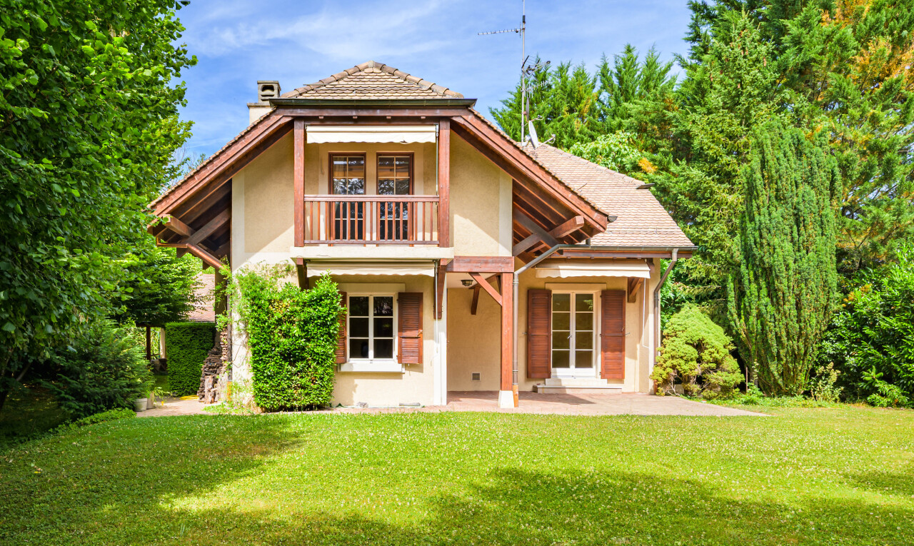 outdoor house featuring a chimney, a balcony, stucco siding, and a yard