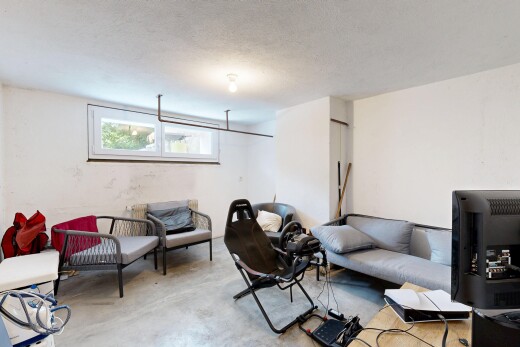 salon avec sol en béton, concrete floor, sous-sol, télévision, et lumière naturelle