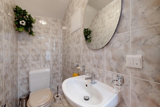 salle de bains avec toilette, mur en carrelage, tile wall, évier, et miroir