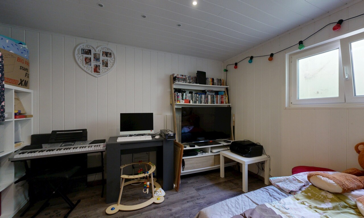 zimmer / schlafzimmer mit bürobereich, holzfußboden, wood finish floor, fernseher, und natürliches licht
