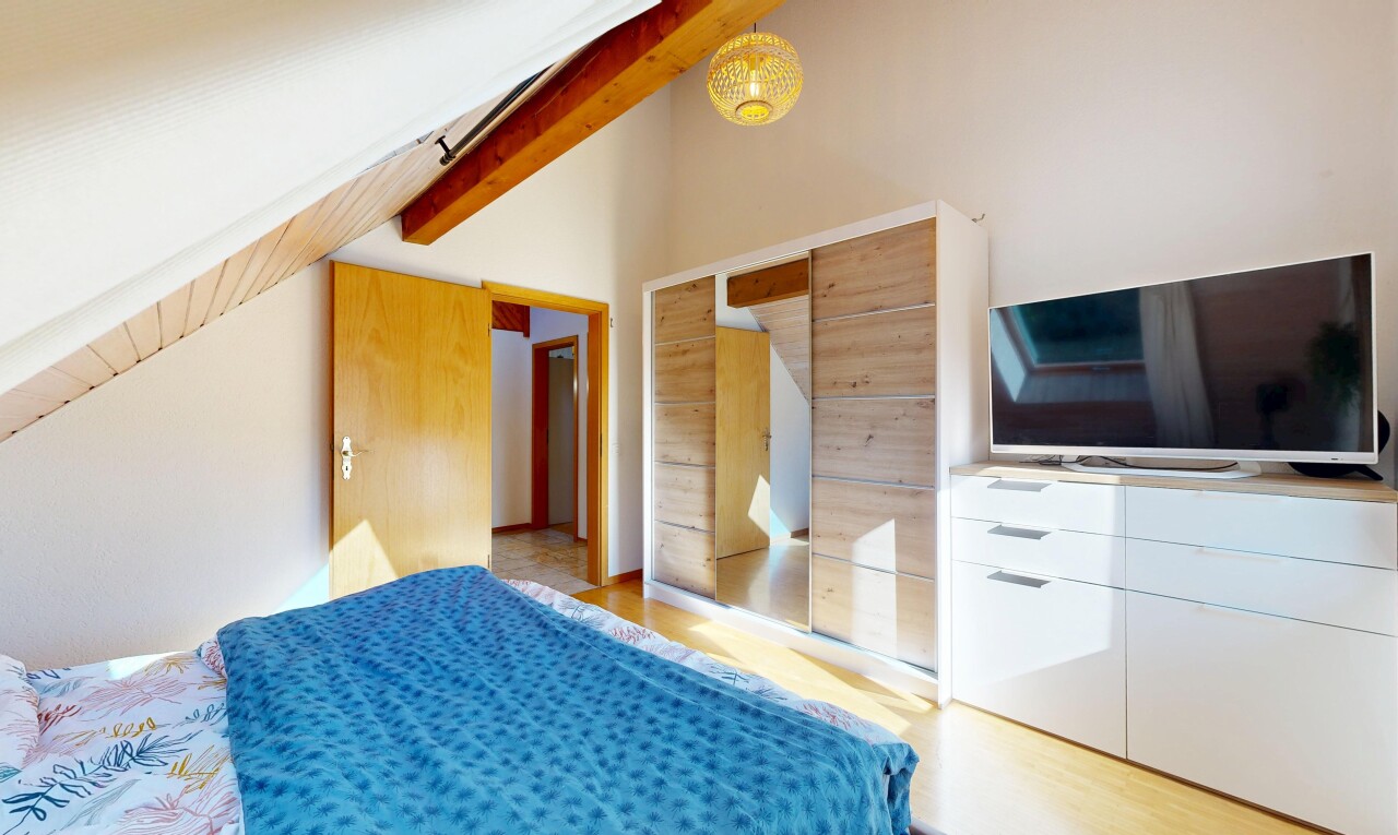 zimmer / schlafzimmer mit fernseher, light floor, holzfußboden, wood finish floor, und balkendecke