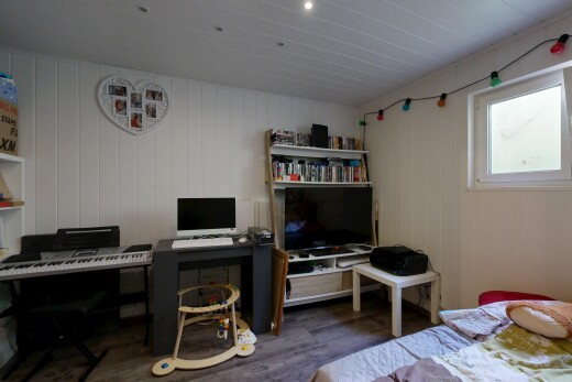 zimmer / schlafzimmer mit bürobereich, holzfußboden, wood finish floor, fernseher, und natürliches licht