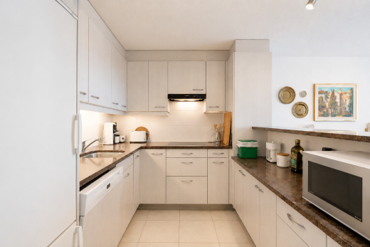 cuisine avec réfrigérateur, micro-ondes, dark countertops, light floor, et inside property