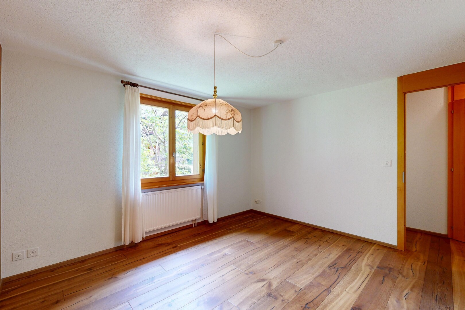 empty room with light wood-type flooring, radiator heating unit, and a textured ceiling