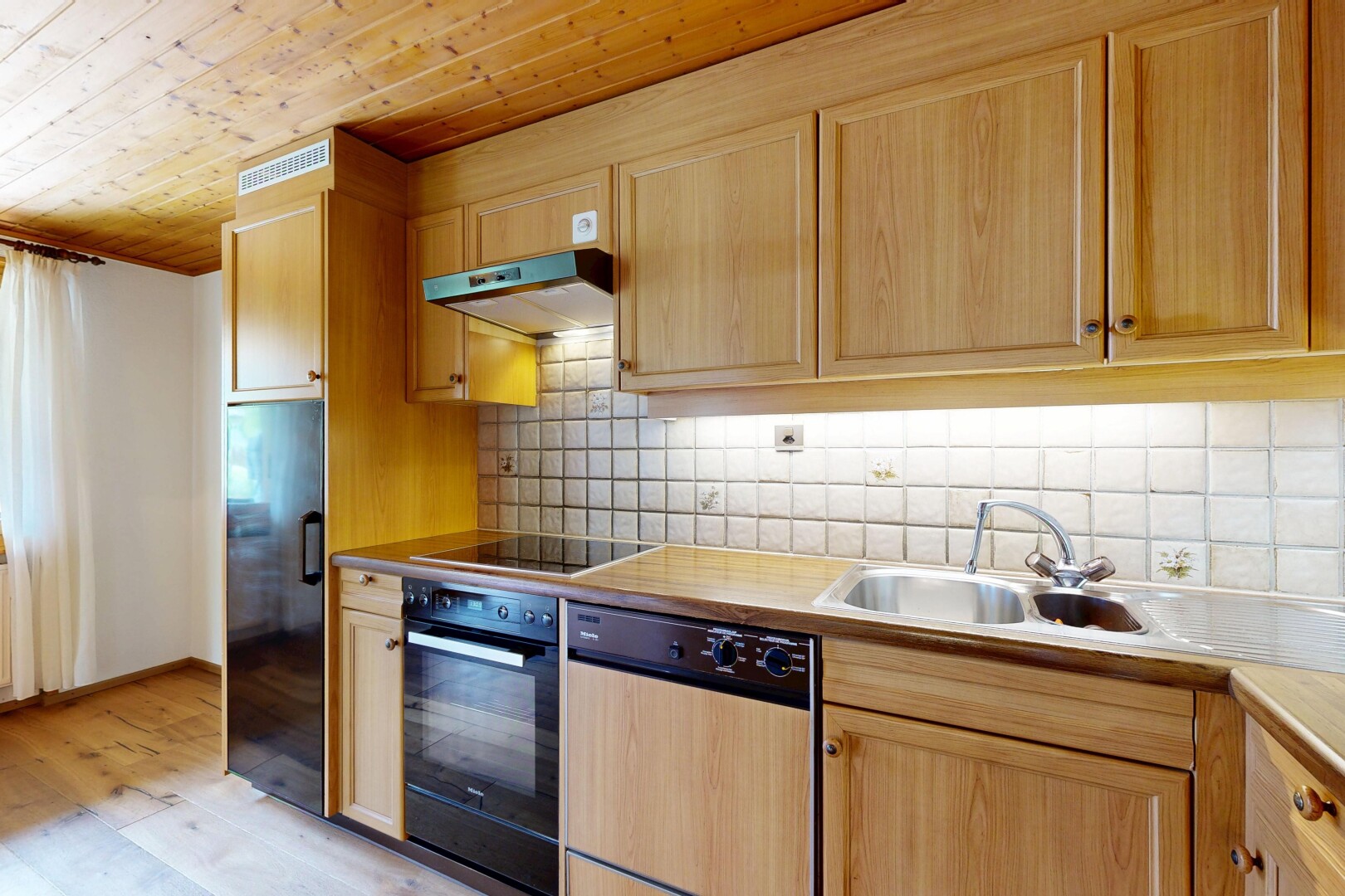 kitchen with light wood finish cabinetry, black appliances, wood ceiling, tasteful backsplash, and light countertops