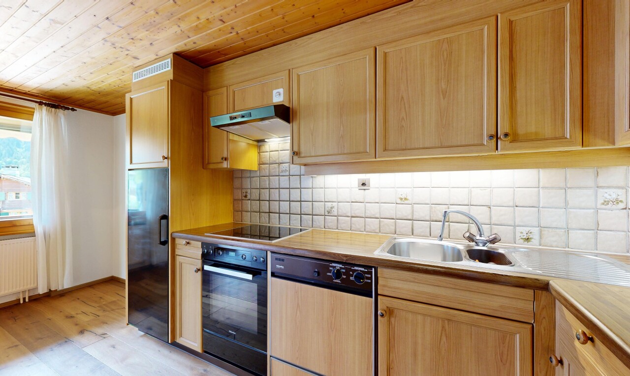 kitchen with light wood finish cabinetry, black appliances, wood ceiling, tasteful backsplash, and light countertops