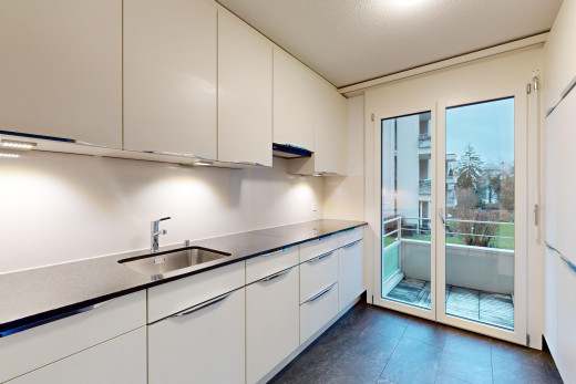 küche mit arbeitsplatten, natürliches licht, weiße schränke, waschbecken, und fliesenboden